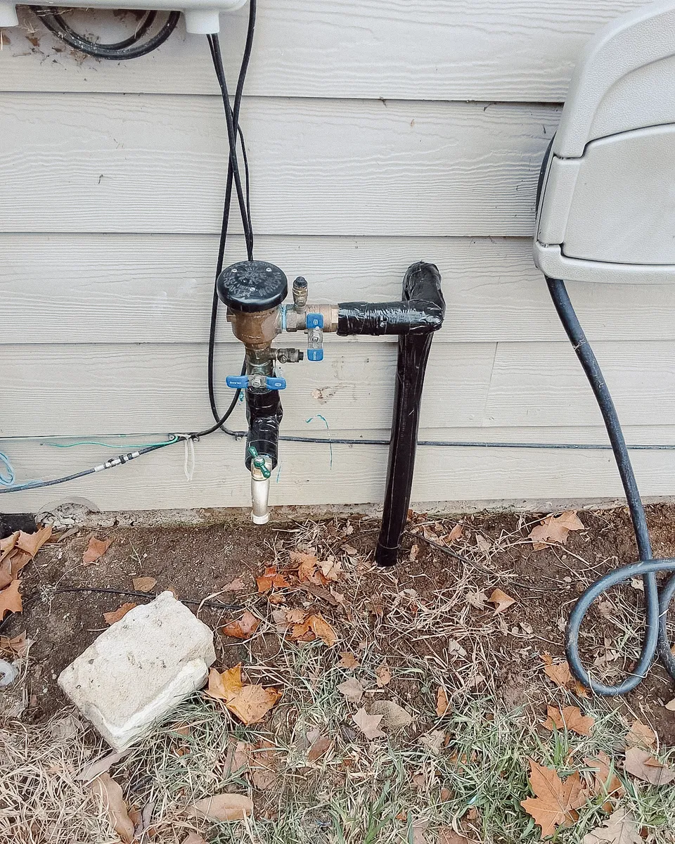 New brass irrigation backflow preventer with fresh insulated piping on the same wall