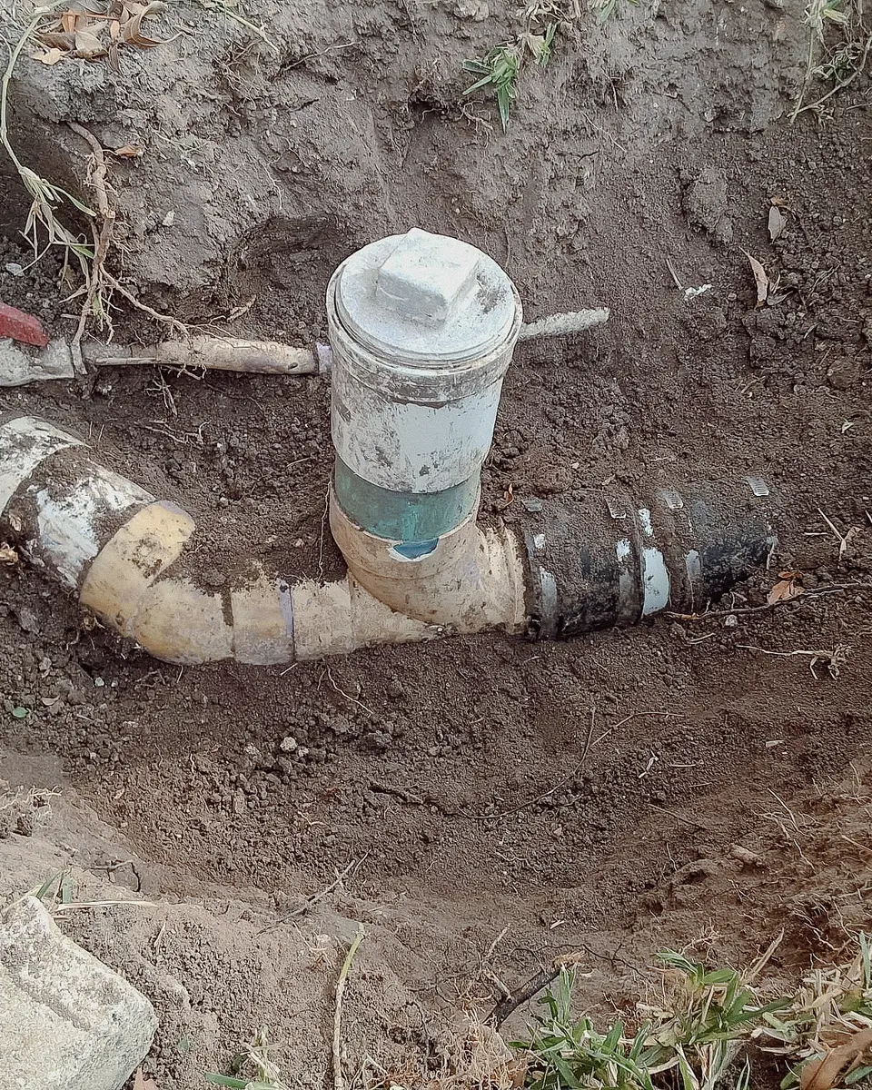 Cracked, stained sewer cleanout fittings in the dirt